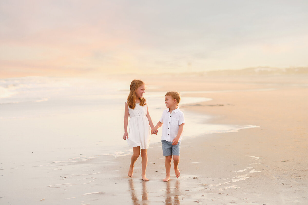 Siblings walk hand in hand during Family Pictures on Isle of Palms. 