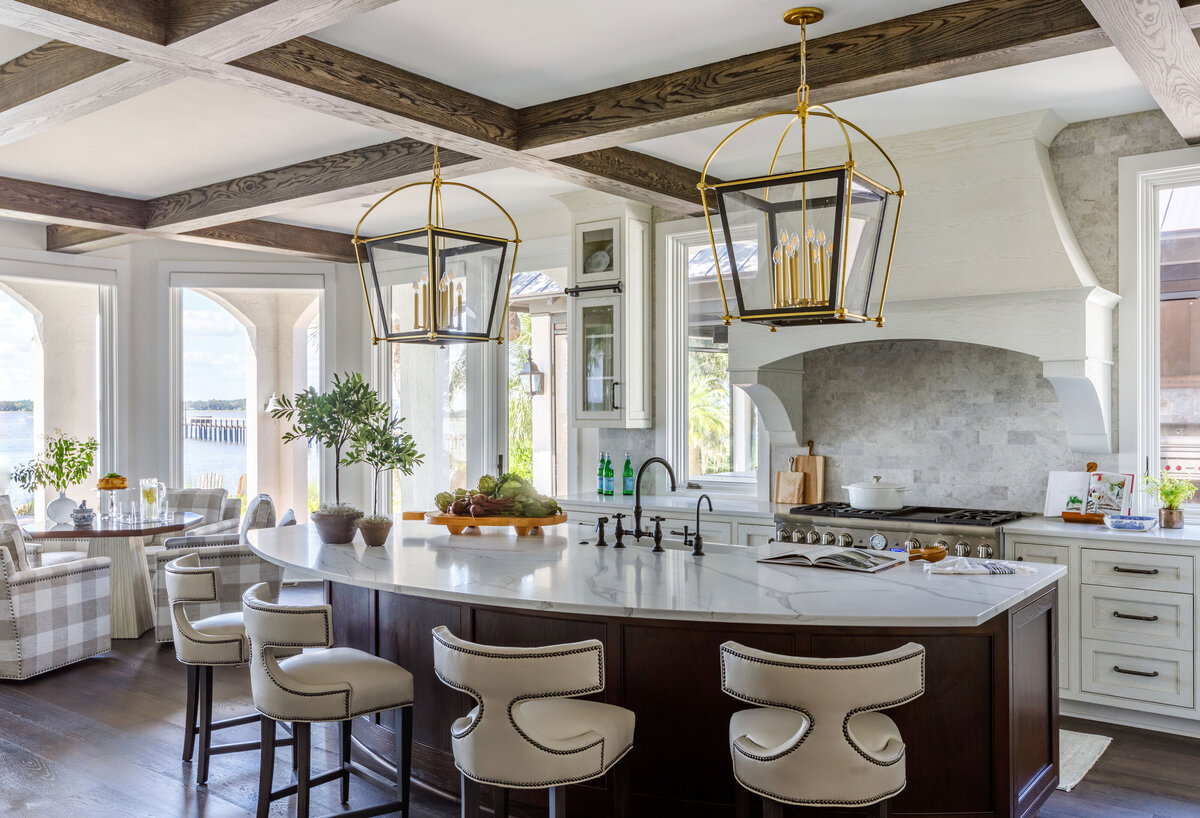 A large kitchen with two chandeliers and a curved bar in the middle