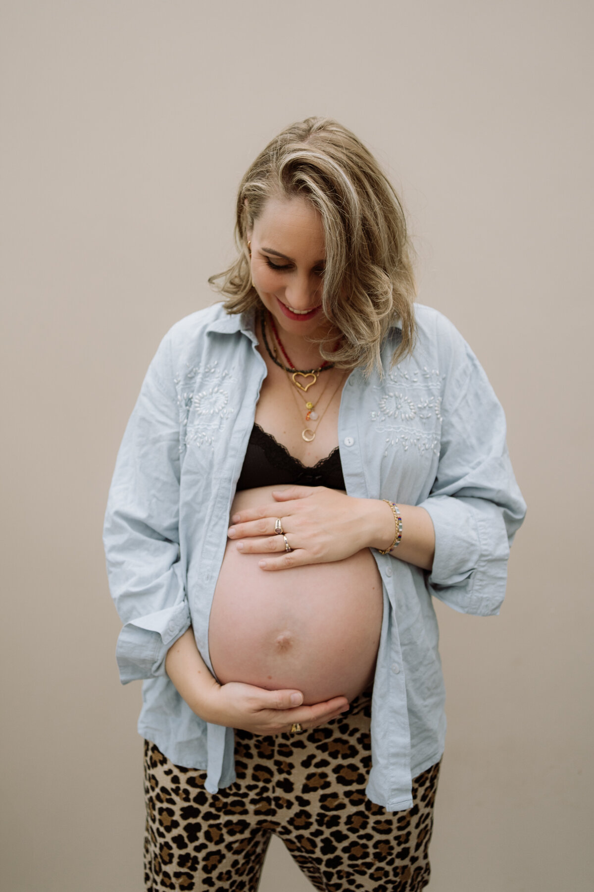 Sfeervolle zwangerschapsfoto van een vrouw met een prachtig zichtbare buik, vastgelegd in een warme en authentieke setting.