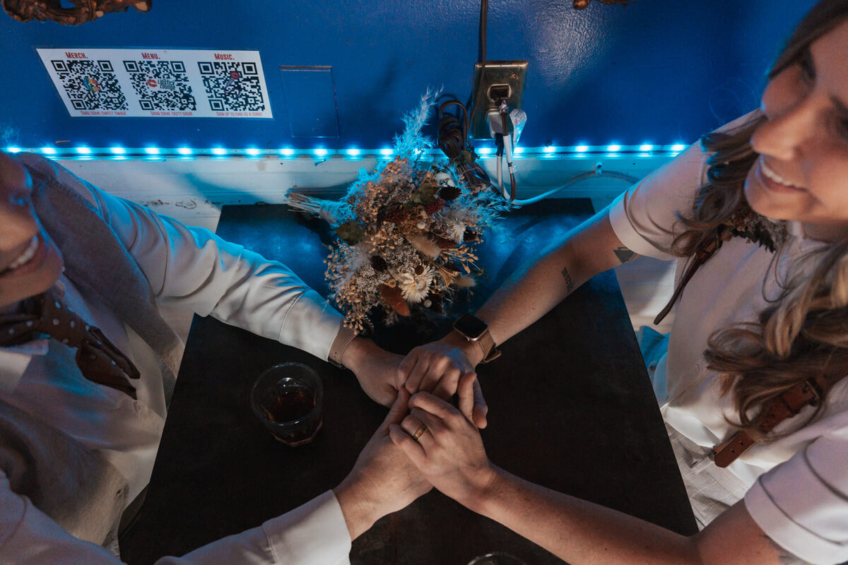 Women hold hands on bar top in a Nashville Lesbian bar 