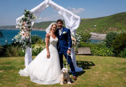 A bride and groom pose for a picture with their dog