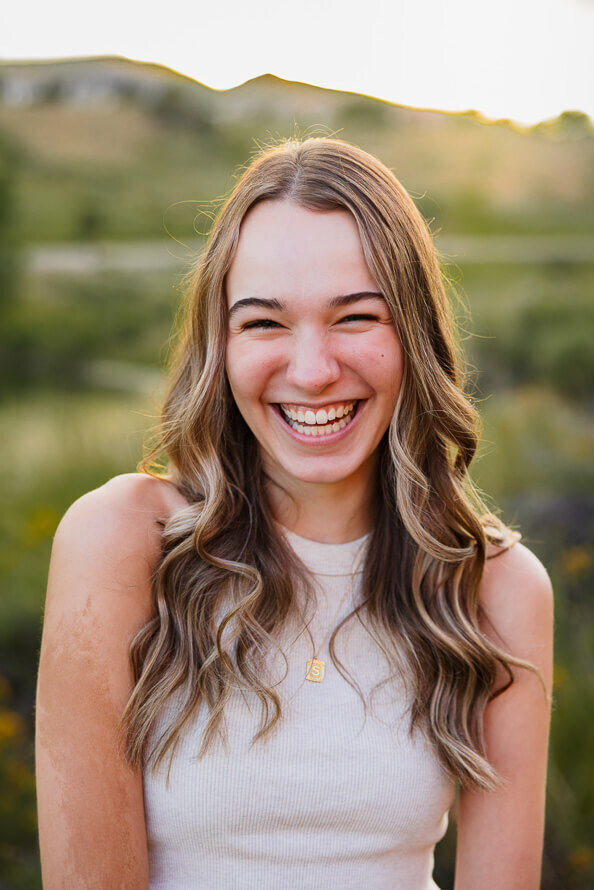 Closeup of girl in white tank and long hair laughing.