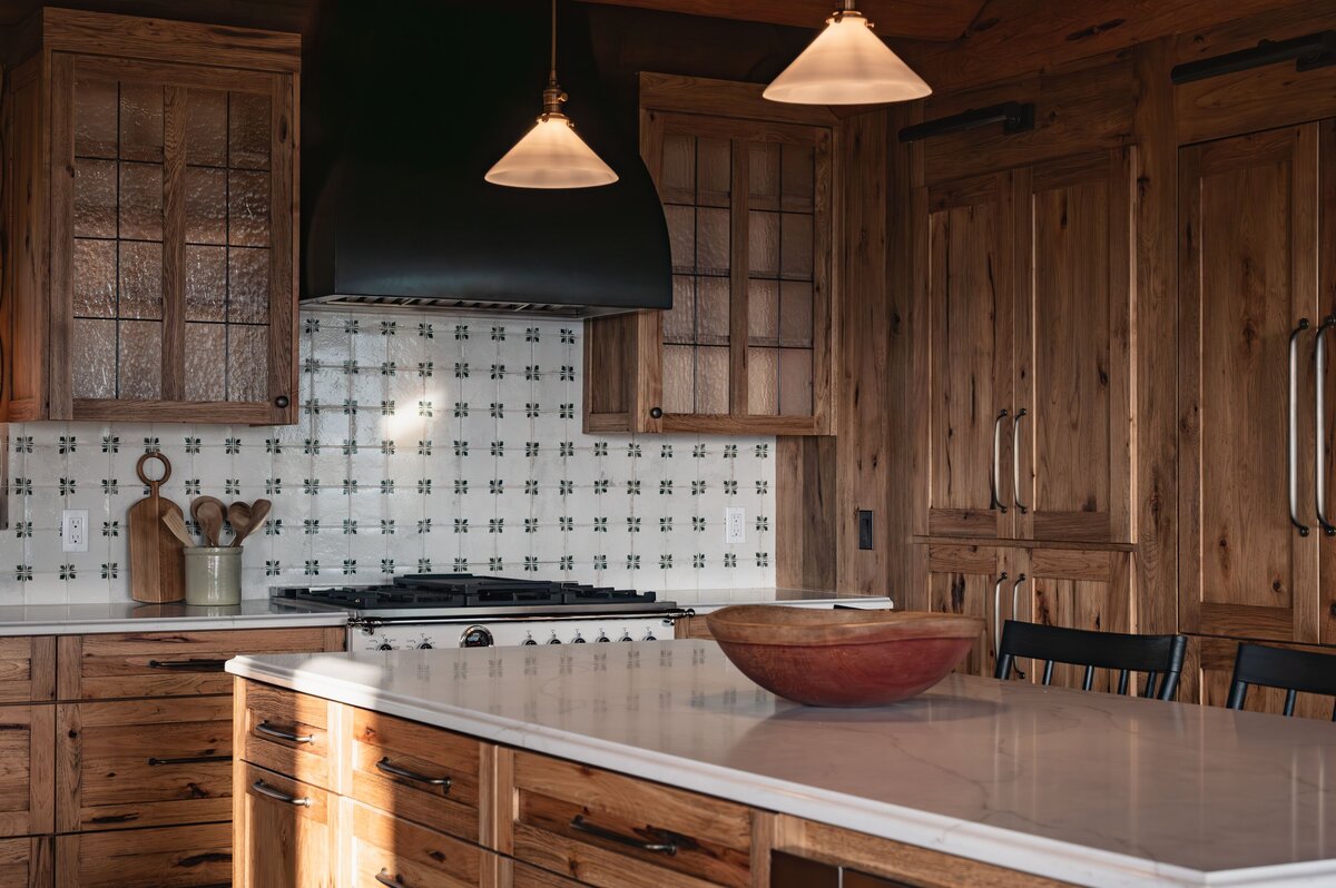 Rustic kitchen with wood cabinets, patterned tile backsplash, and large island, Photo by Moore Creative.