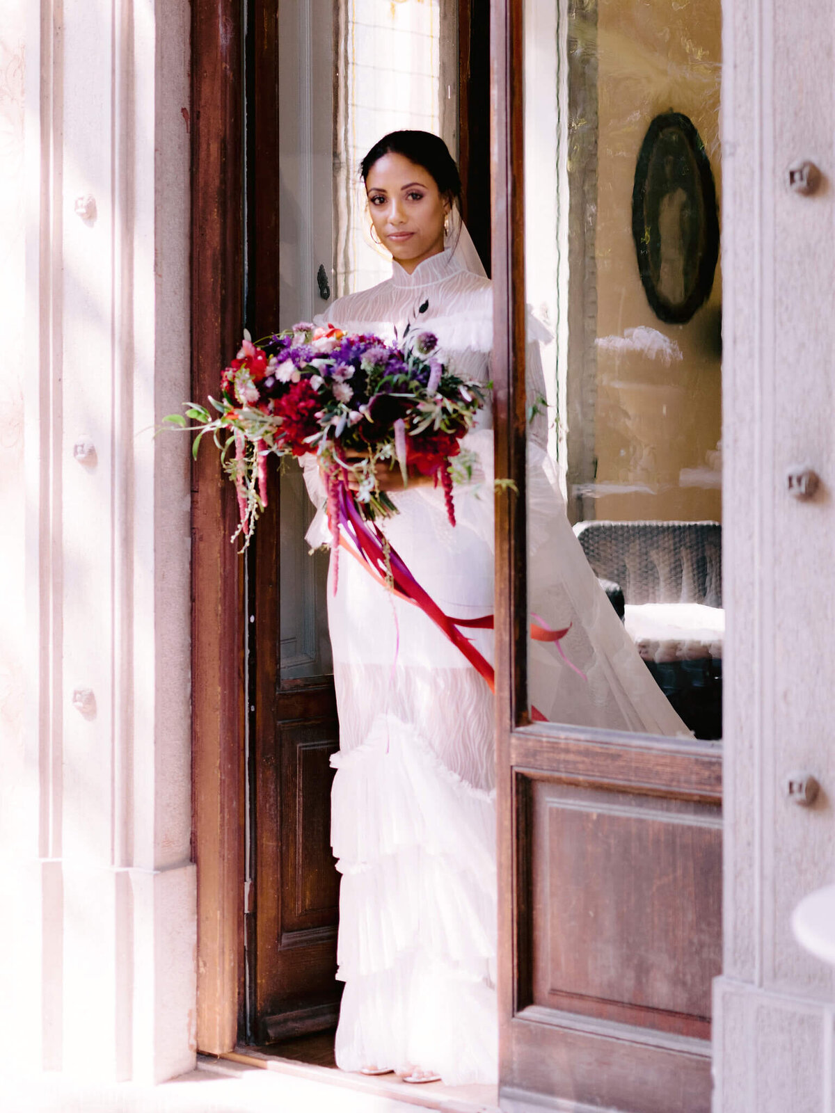 Bride holding a flower bouquet, standing on a door