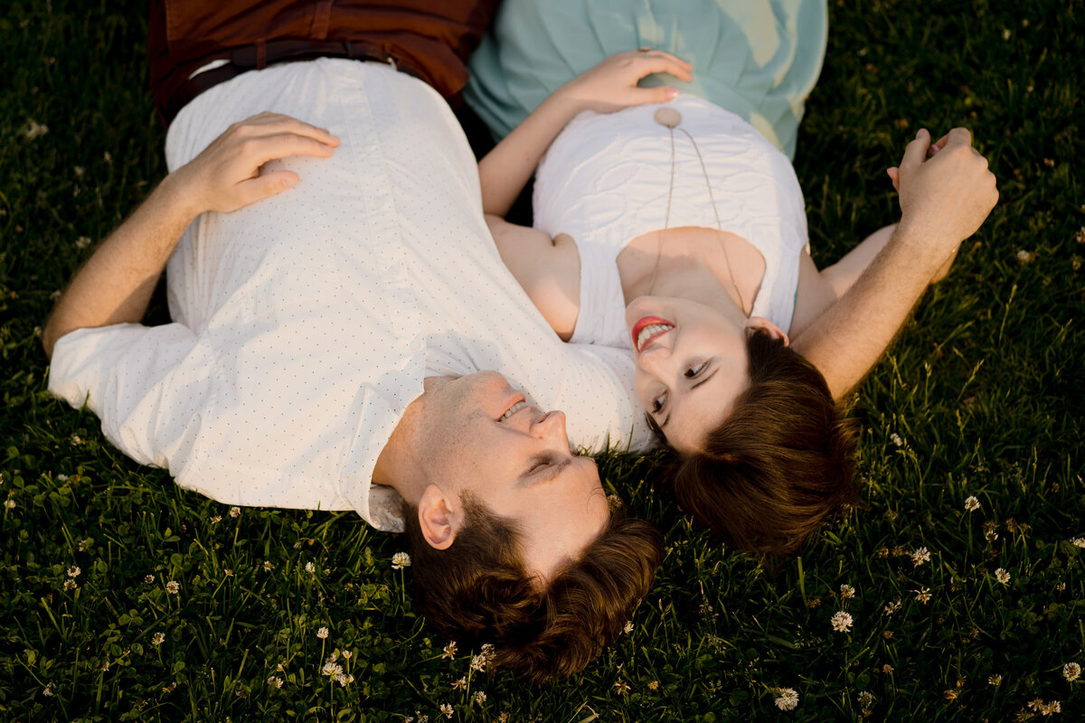 A couple cuddling while laying in the grass.