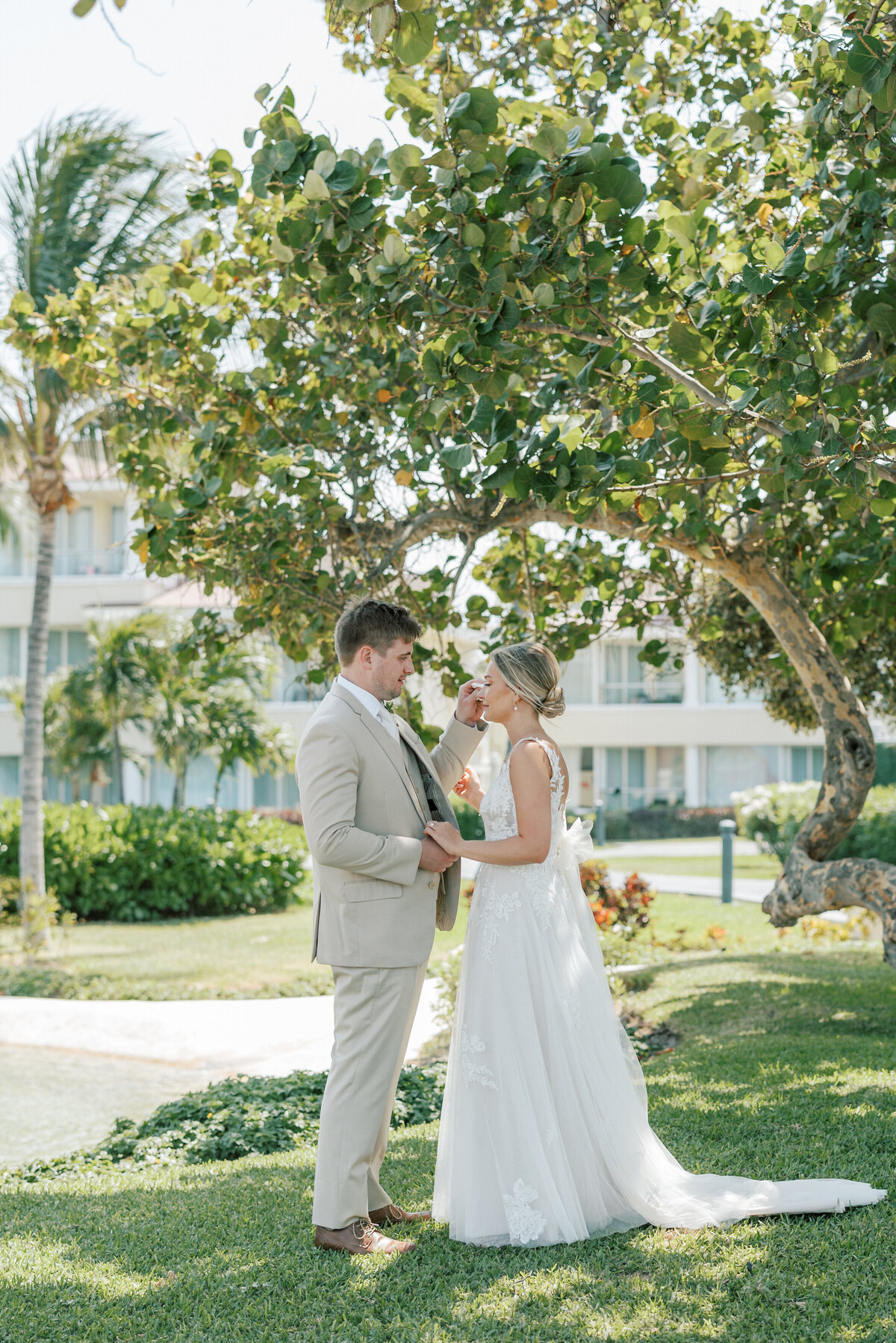 Romantic moment under a tropical tree during a Cancun wedding first look, photographed by Philly-based Olivia Casey.