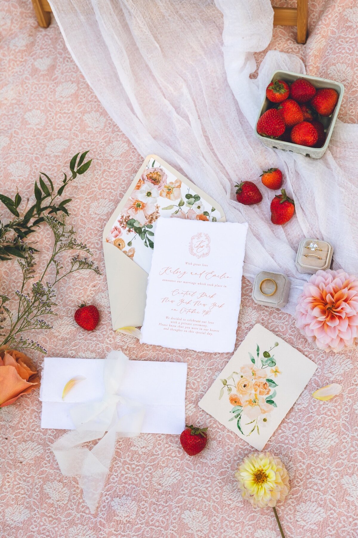 Picnic-inspired flat lay of wedding invitations and strawberries