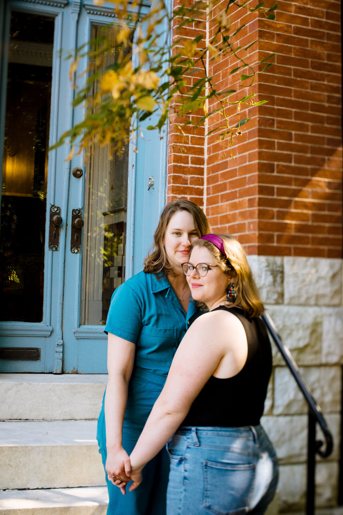 A person standing on a staircase holding hands with their partner who is standing at the bottom of the stairs.