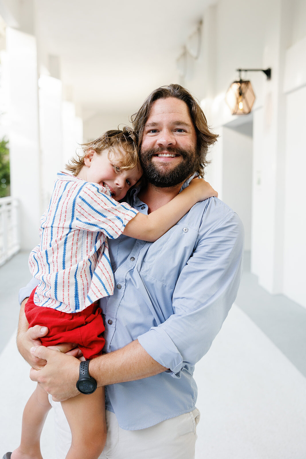 A father holds his smiling son close in a warm embrace during a family portrait session in the Florida Keys.
