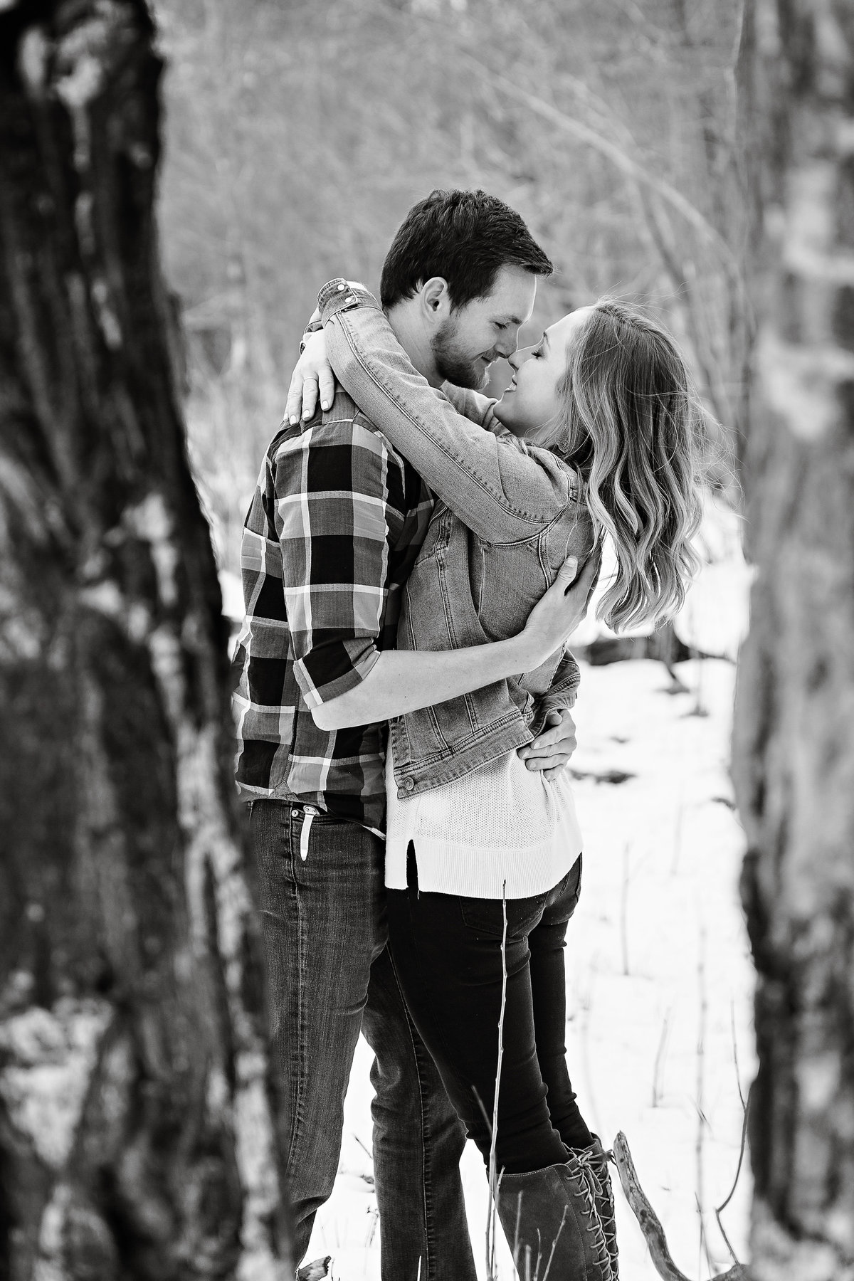 Fun black and white photo of engaged couple hugging tight in the snow