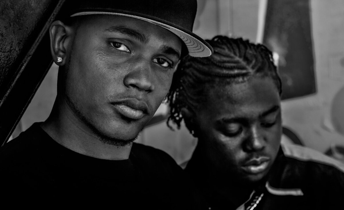 Musical duo portrait Therapist leaning against Fiyah MC black and white close up