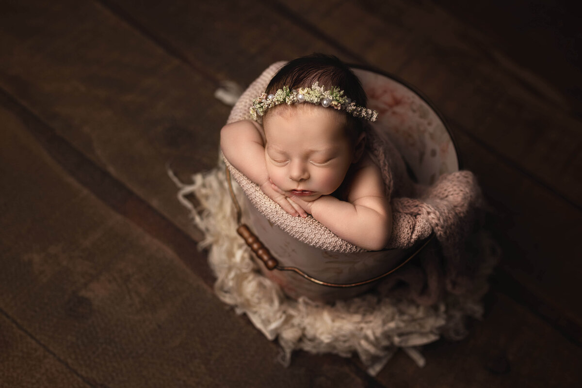 Newborn girl sleeping  in bucket