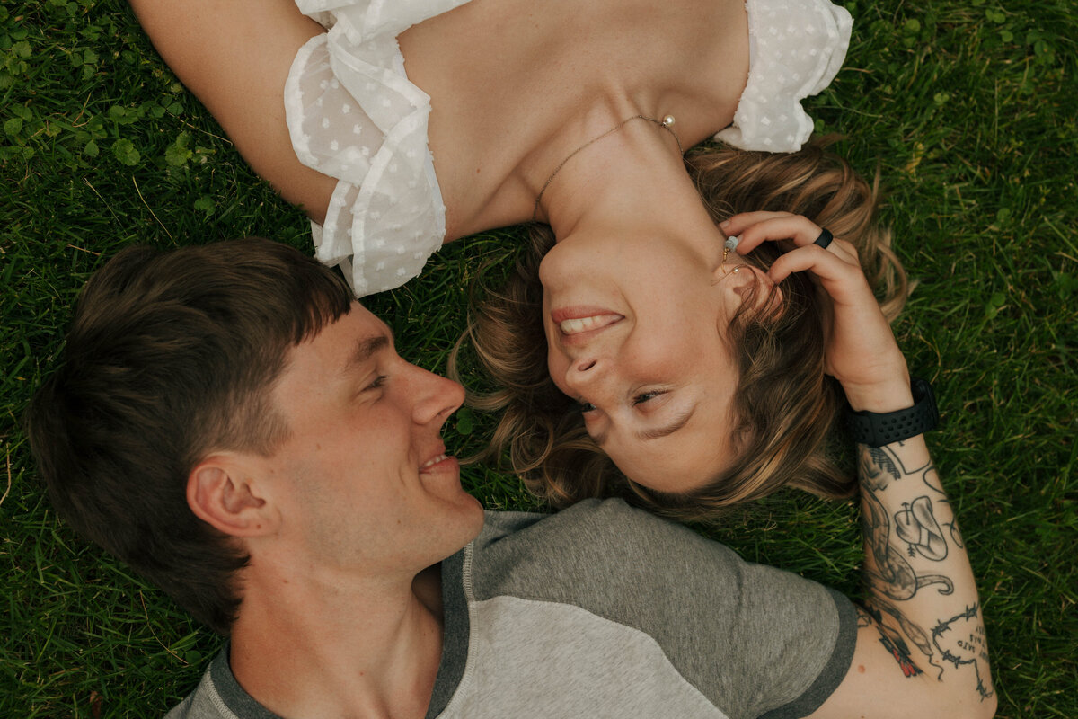 Couple laying in the grass at their Dayton, Ohio engagement by April Graber Photography