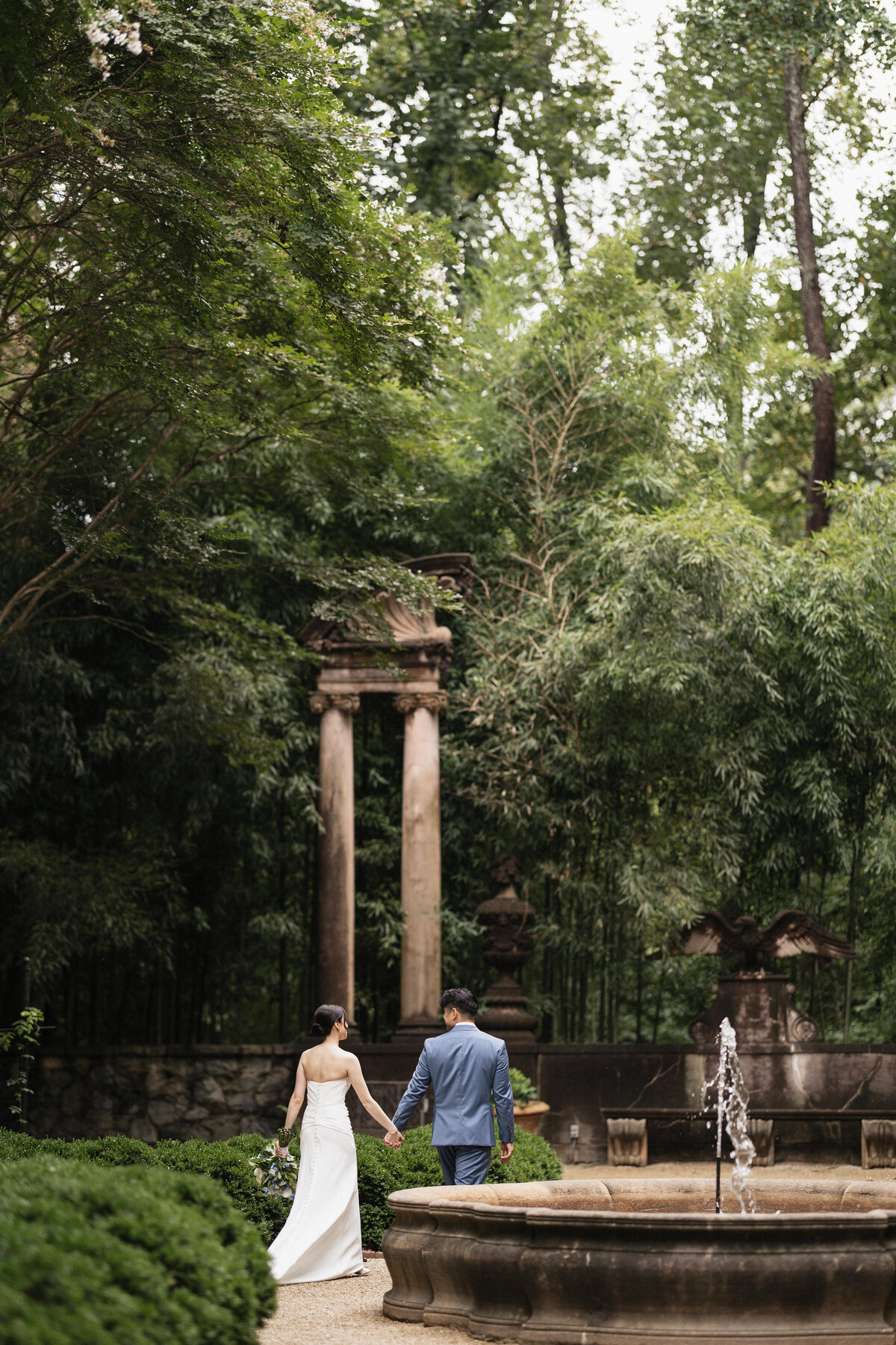 Couple walking through the Swan House garden on their wedding day.
