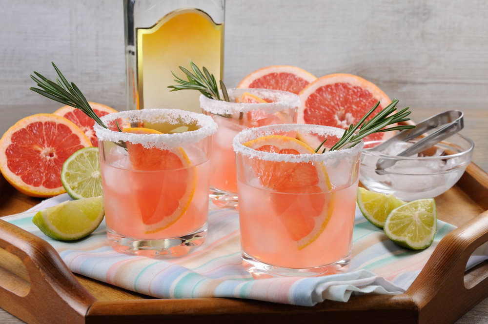 Tray of grapefruit craft cocktails with ice & garnishes