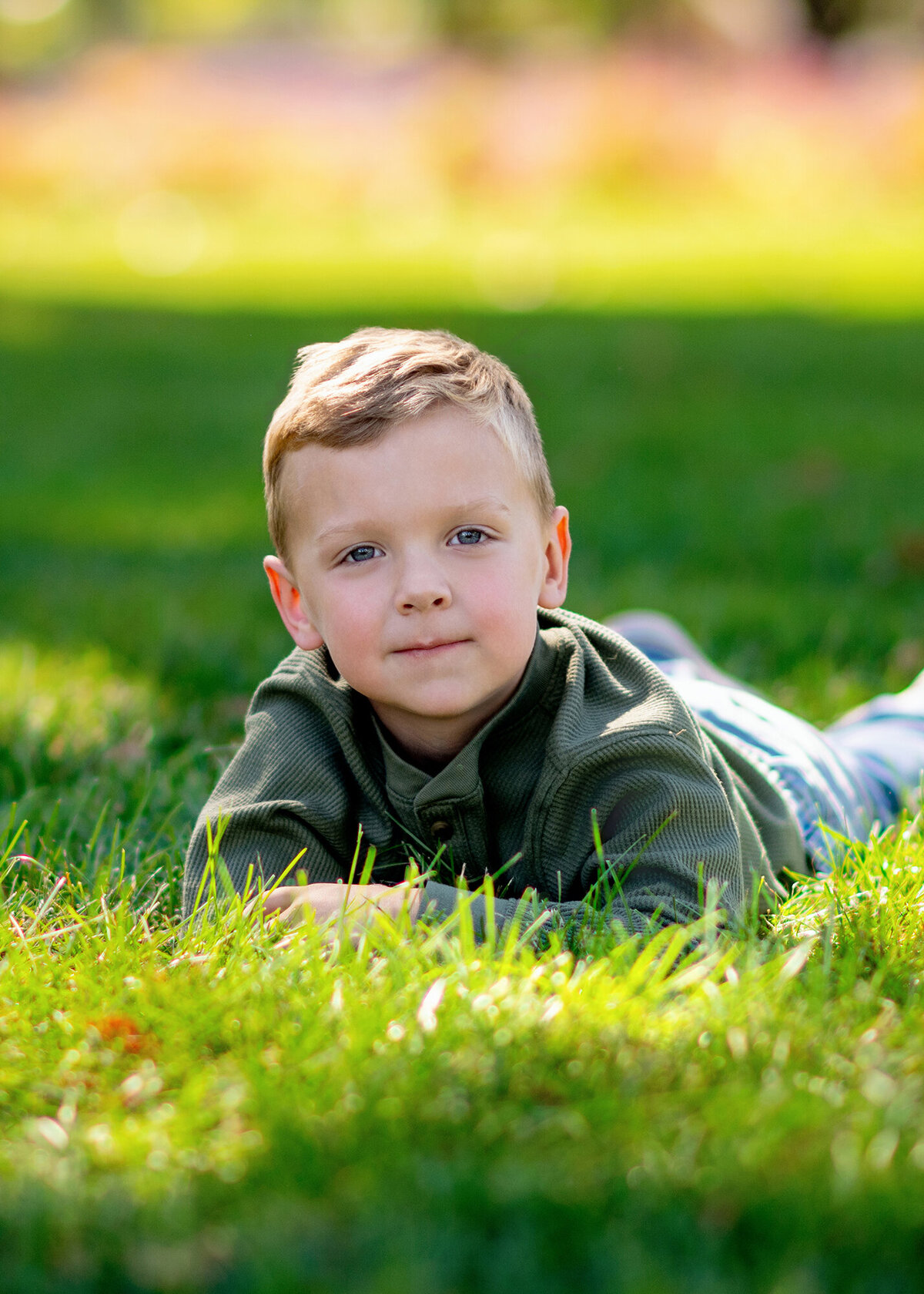 A child lays peacefully on a patch of lush green grass, enjoying the sunshine
