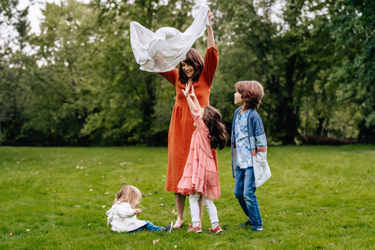 A mom holds up fabric next to three kids.