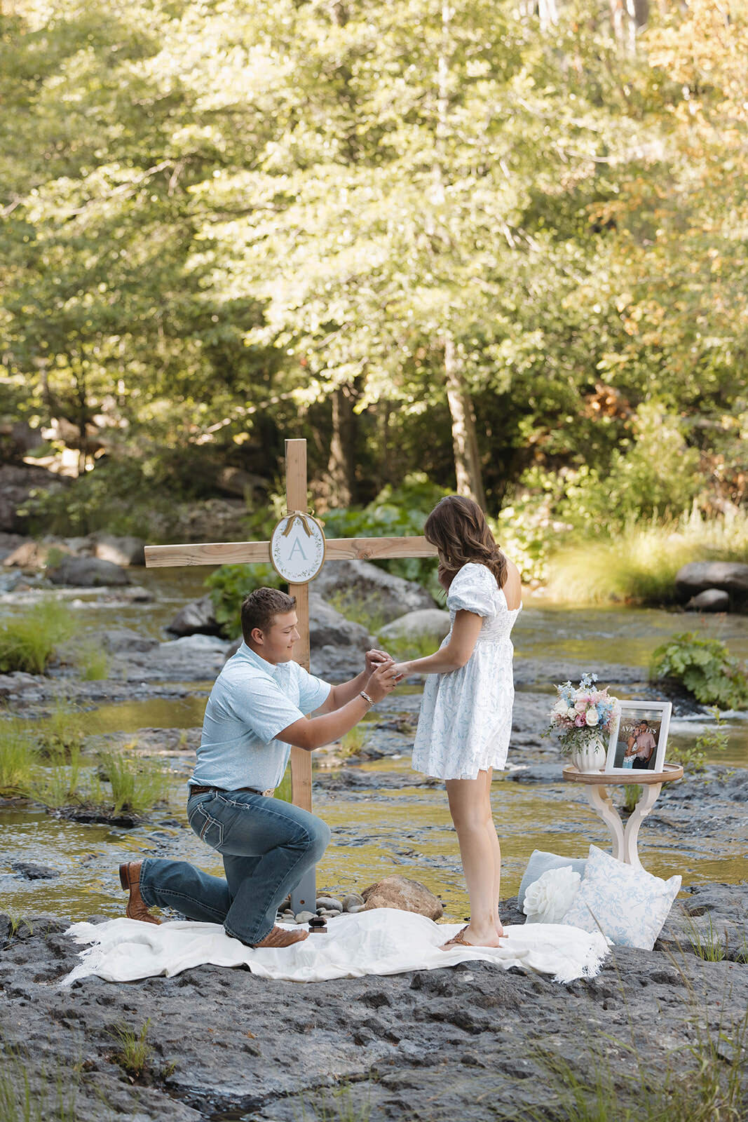 Groom on one knee proposing by a river
