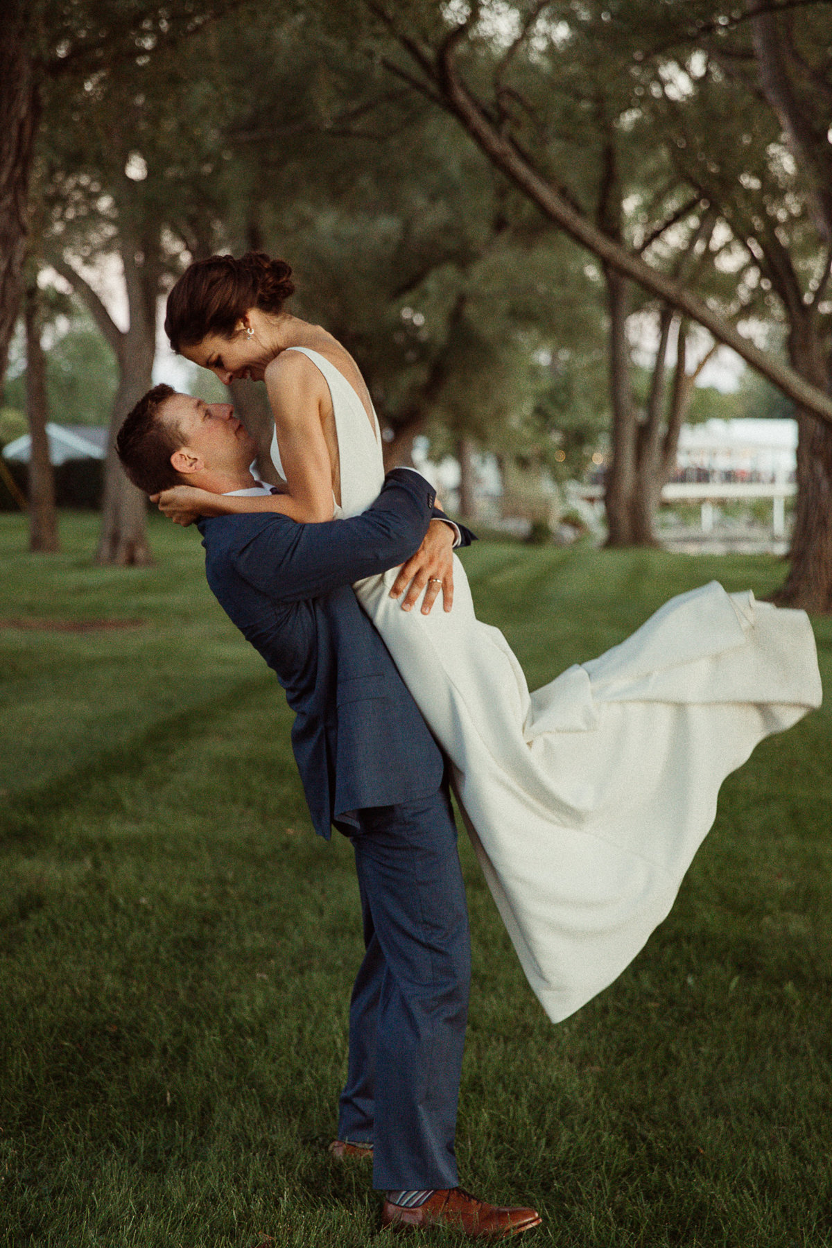 groom in navy blue lifts bride off her feet at Canandaigua Country Club