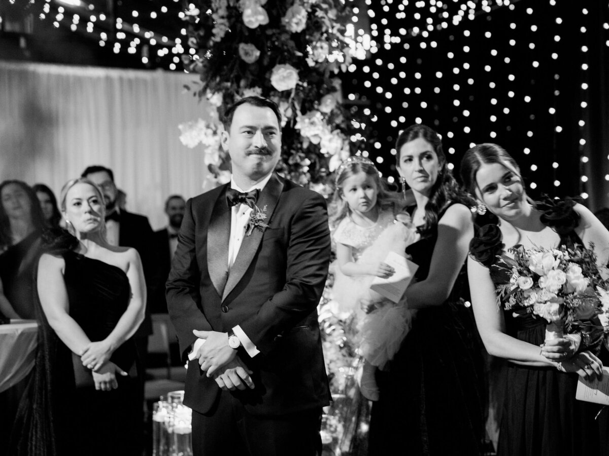 A black and white photo of the groom and bridal party at the reception at the Thether on the Lake. 