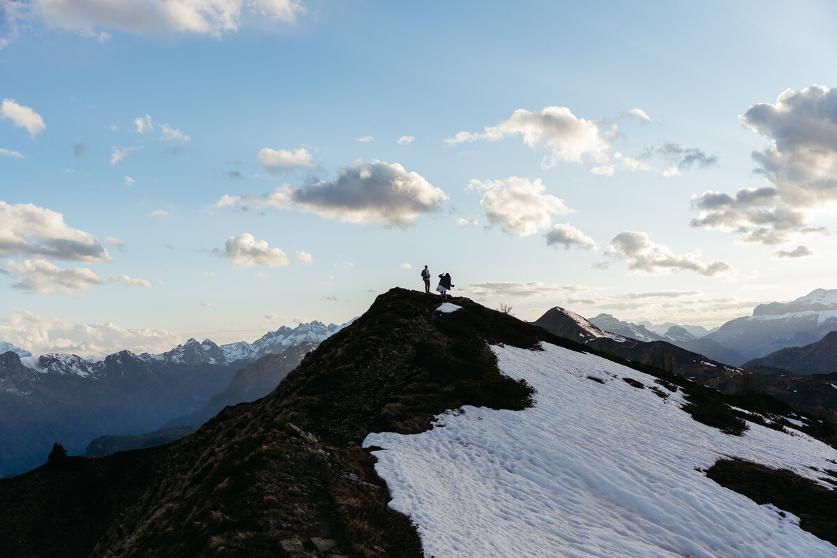 Bride and groom silhouetted on mountain ridge at sunset in Dolomites