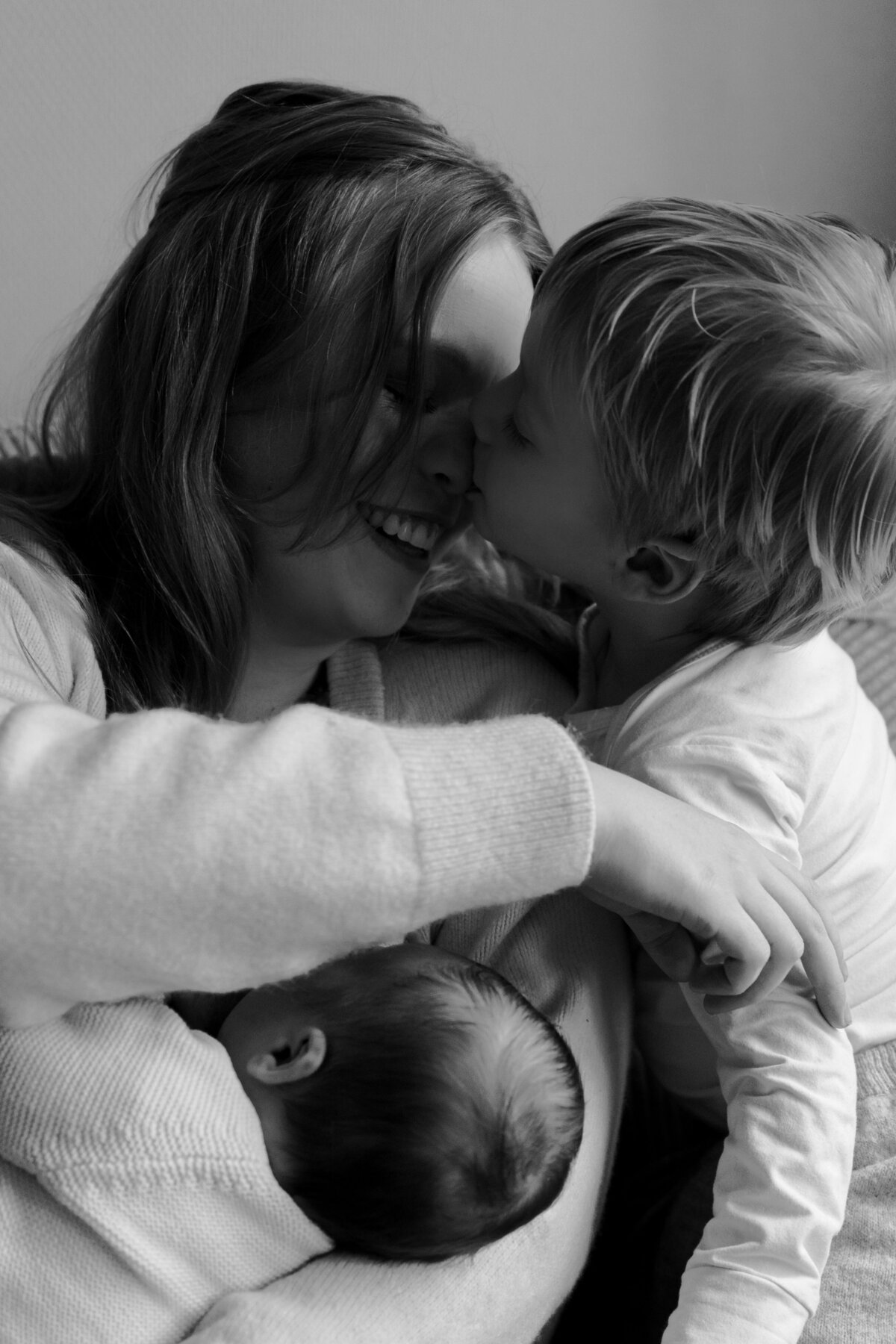  Een vrouw kust twee kinderen, wat een moment van liefde en genegenheid vastlegt.