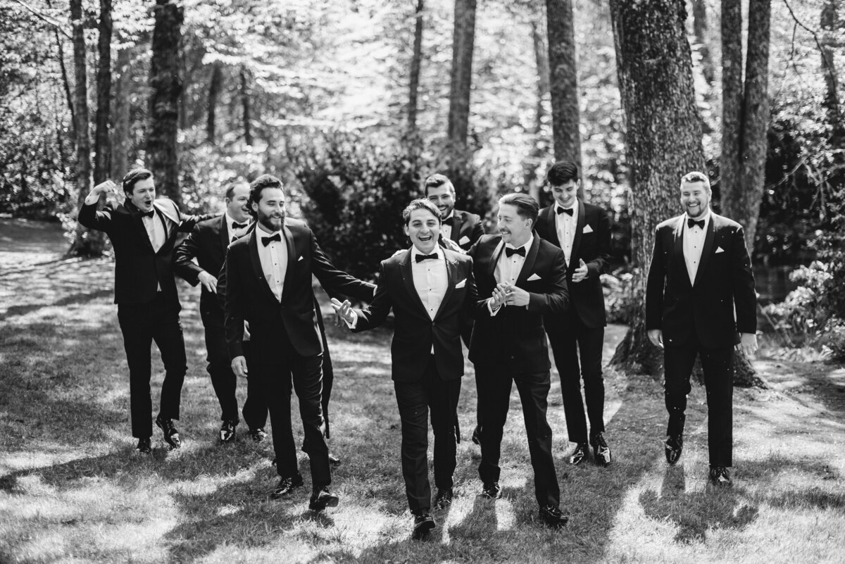 Black and White photo of a groom and his groomsmen walking on a garden lawn at Old Edwards Inn in Highlands, NC. 