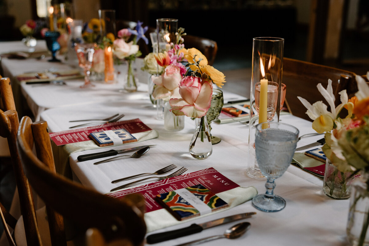 A wedding reception table with small floral arrangements and candles on it 