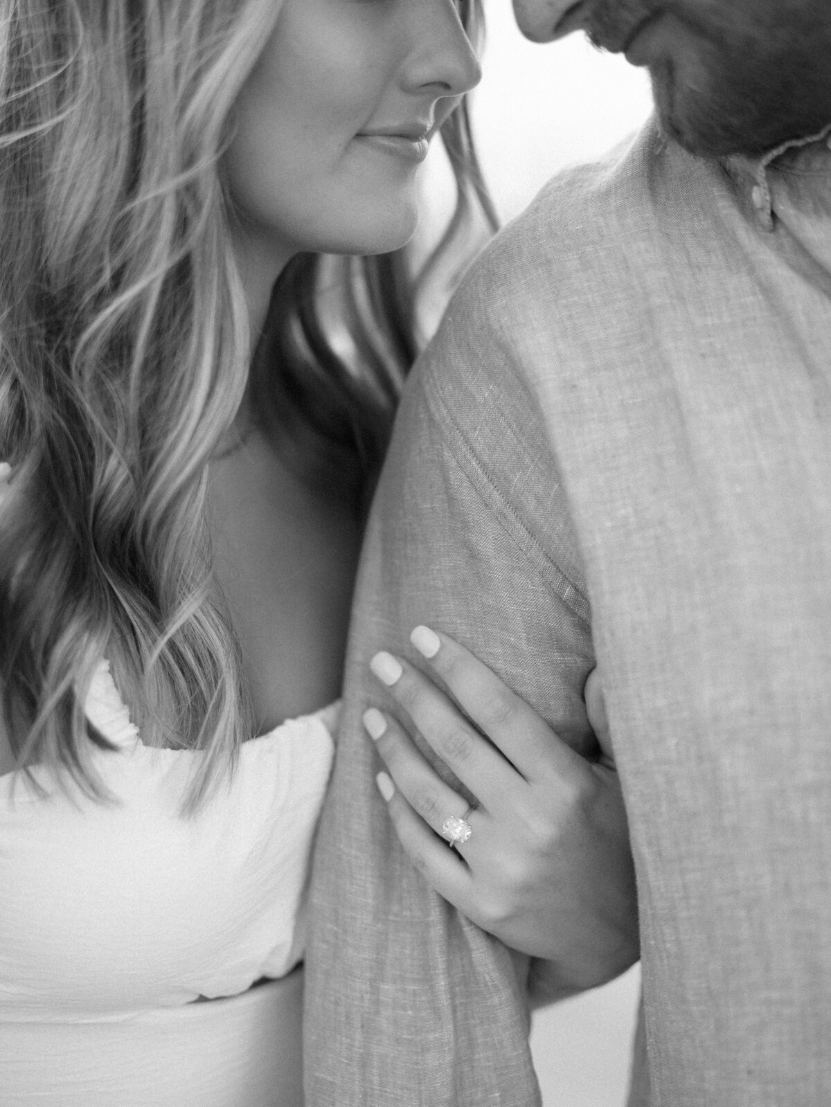 Bride’s engagement ring resting on groom’s arm during Edgewater Beach engagement session

