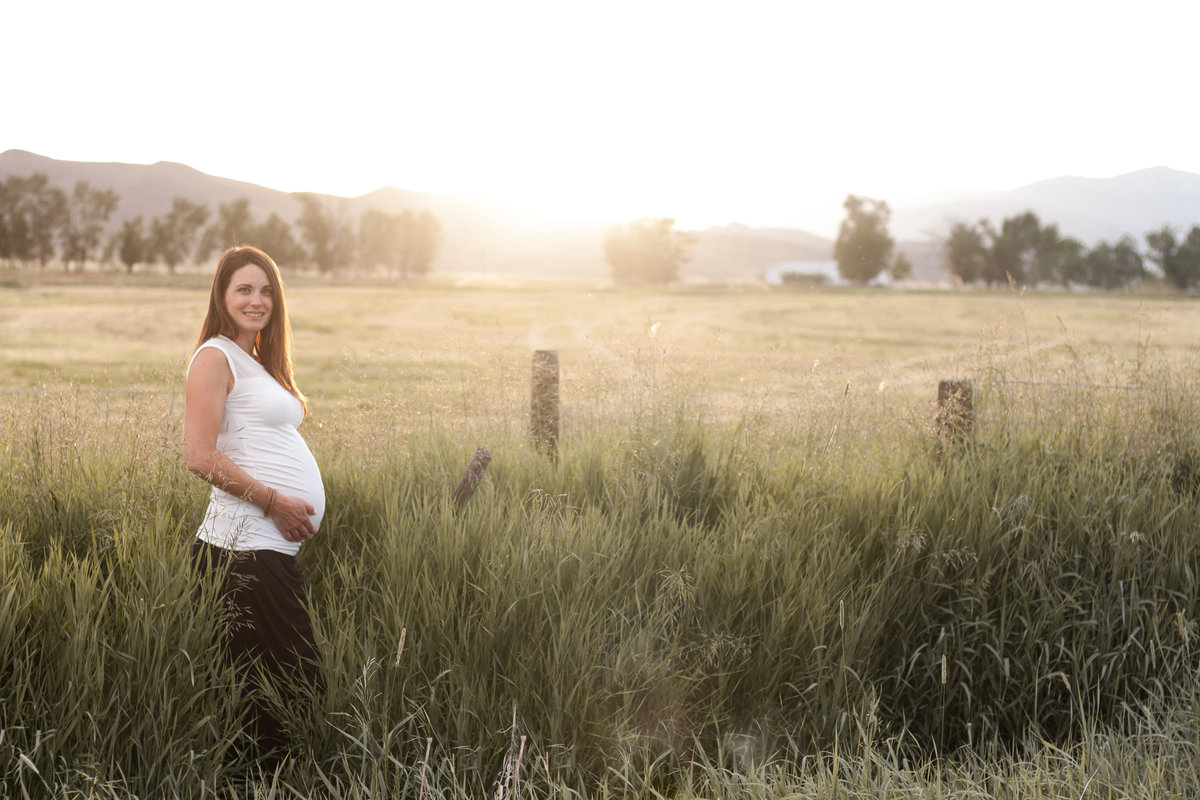 expectant mother in a field at sunset