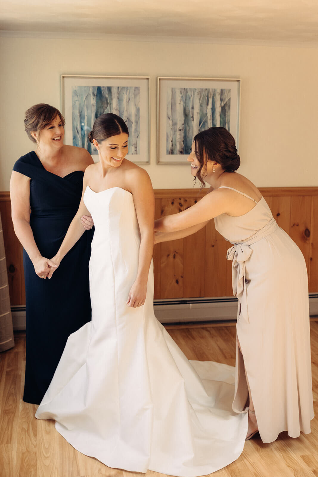 Bridemaid helping bride fix dress at Canandaigua Country Club wedding, NY