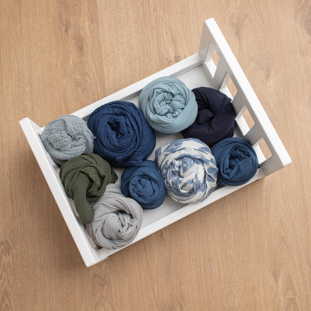 The image is of a newborn photography prop bed with a number of blue shaeded newborn photography wraps.  Image for studio display by Lauren Vanier Photography
