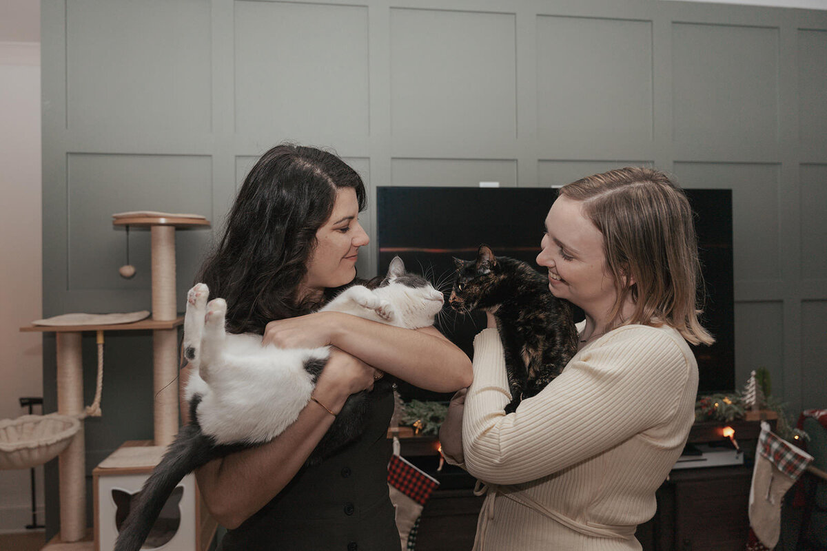 Both women hold a pet cat