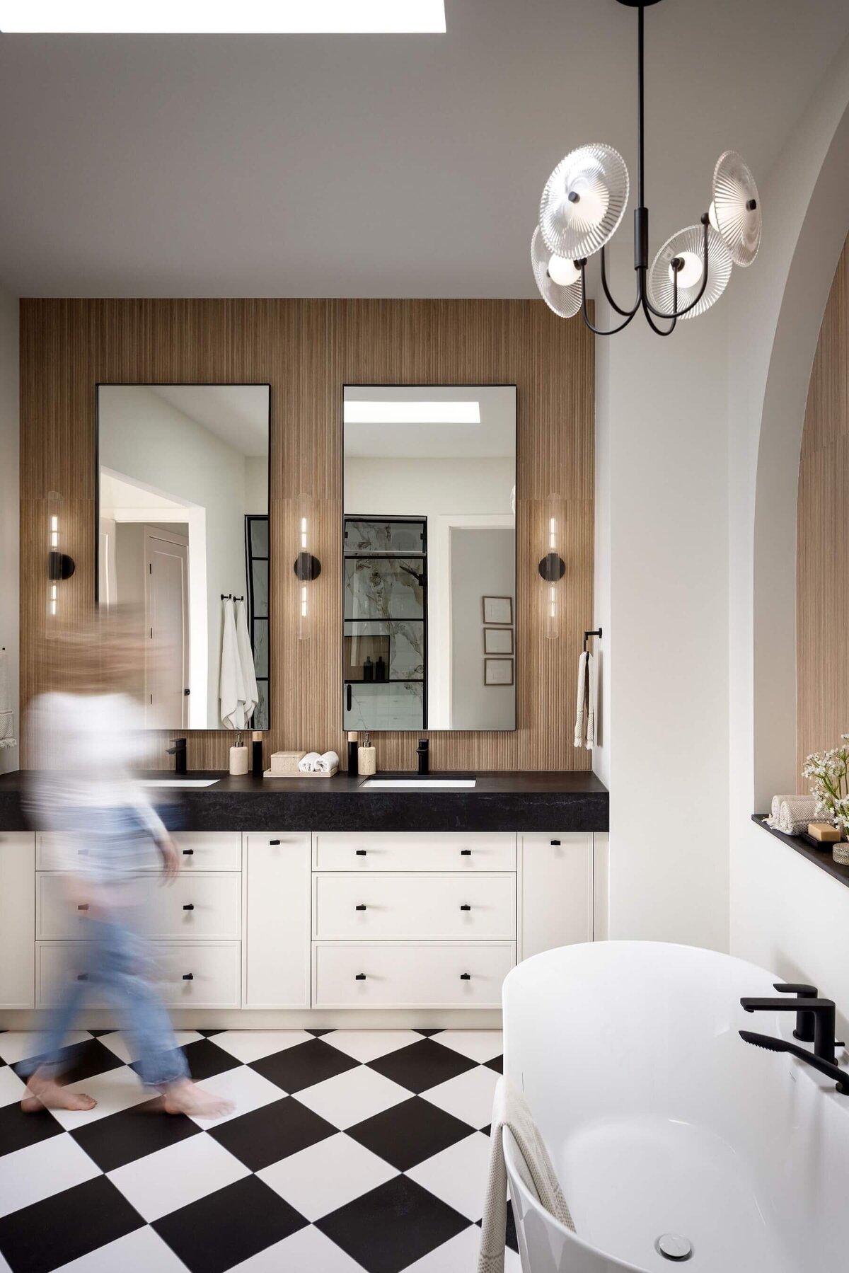 A gorgeous ensuite with black dekton counter tops, natural cream cabinets, black accents and a fluted backsplash tile. 