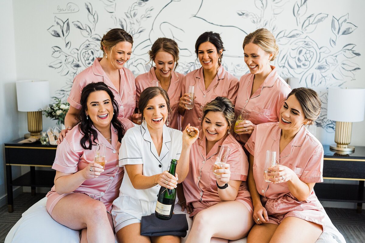 bride and bridesmaids popping champagne in pjs