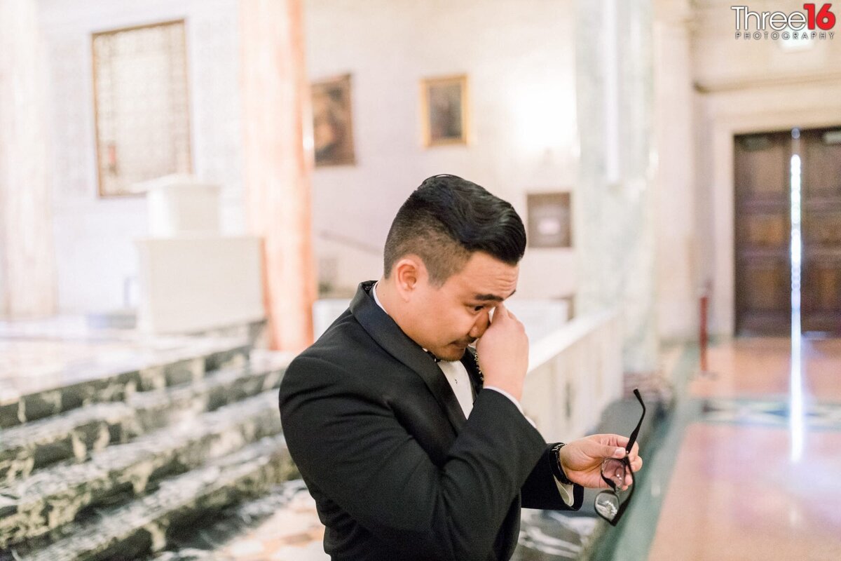 Groom wipes away a tear from his eyes