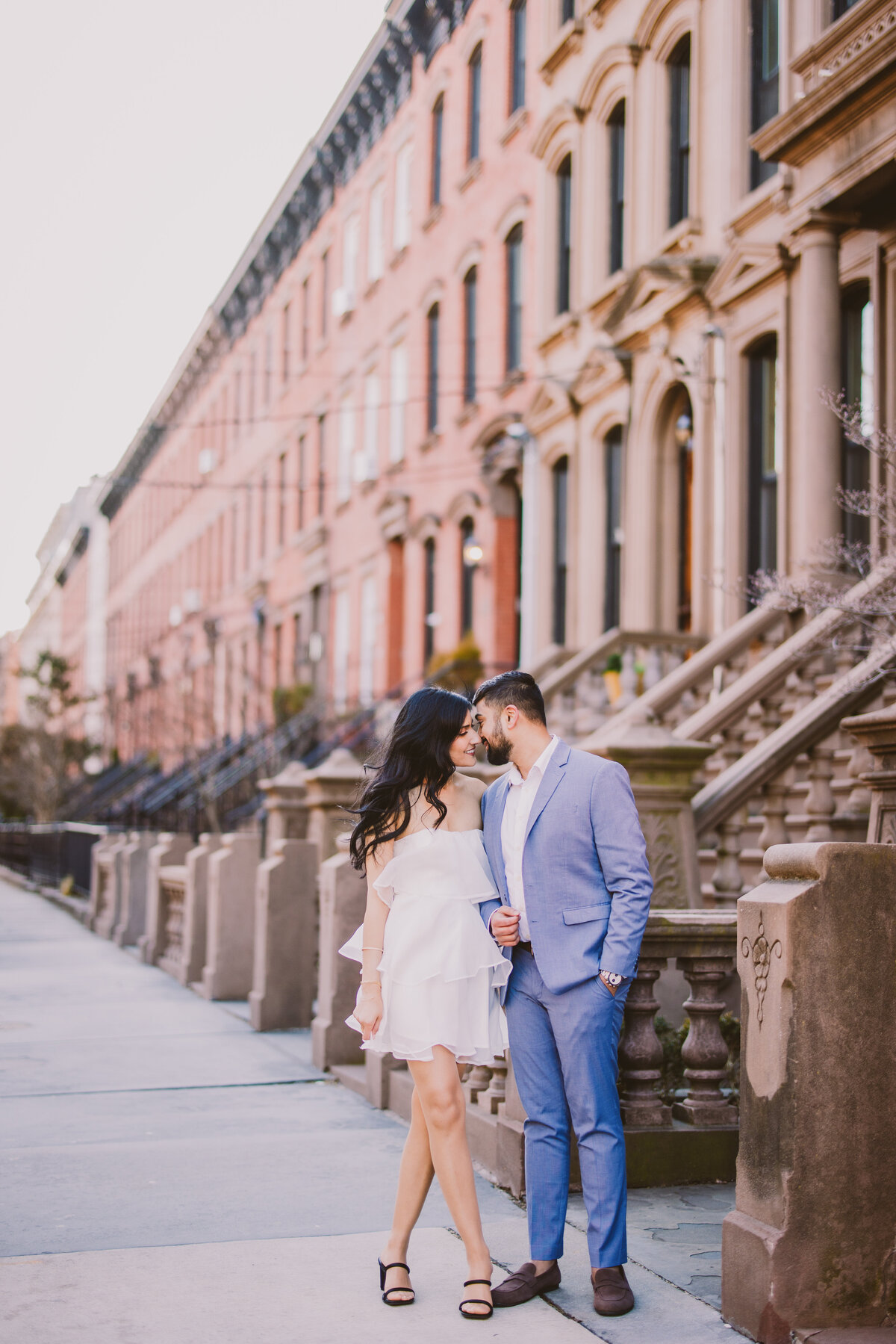 An engagement couple share moment on the street near brownstone buildings in hoboken nj