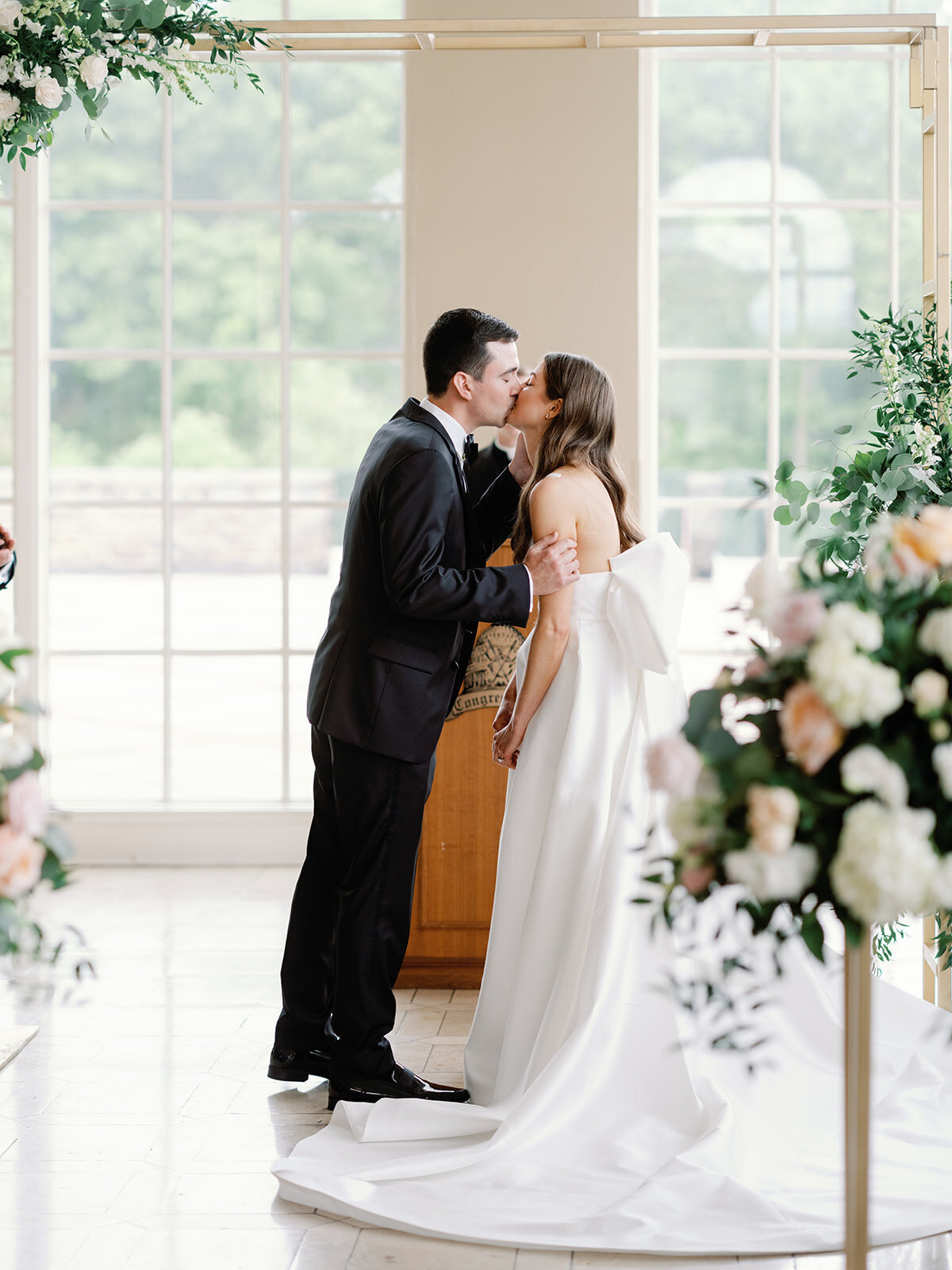 Bride and groom kiss for the first time surrounded by flowers