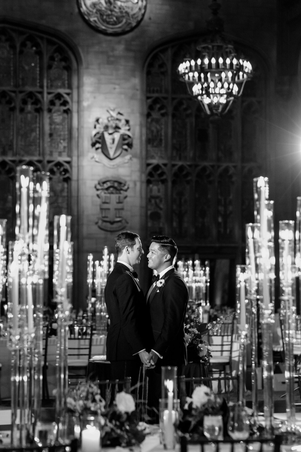 Two grooms embrace surrounded by candlelight