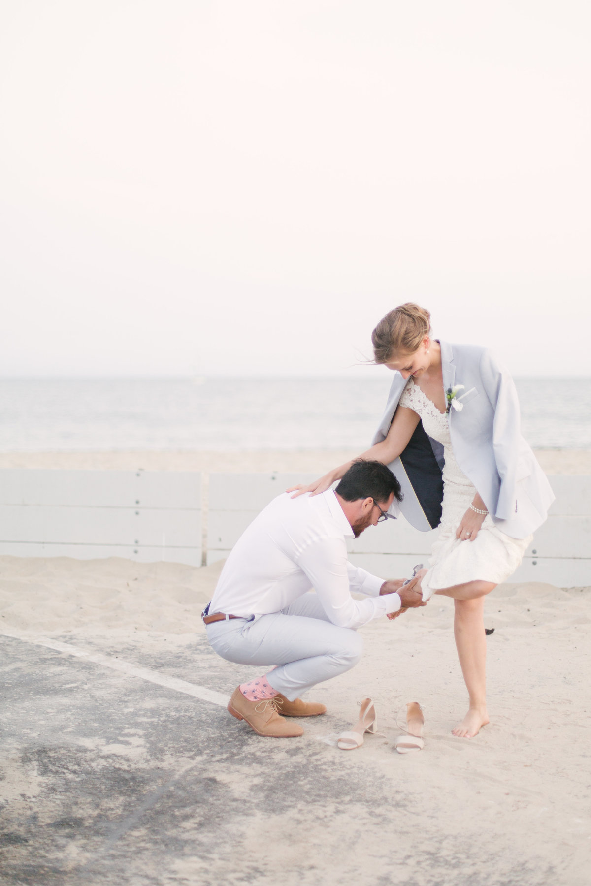Groom helps bride with shoes at Santa Barbara Yacht Club wedding