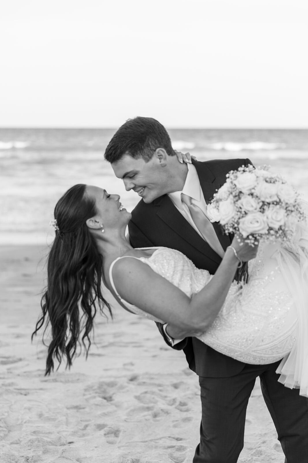 groom dips his bride on the beach