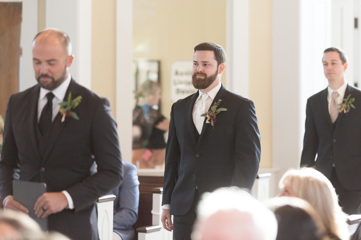 The groom and groomsmen enter the church as the ceremony begins.