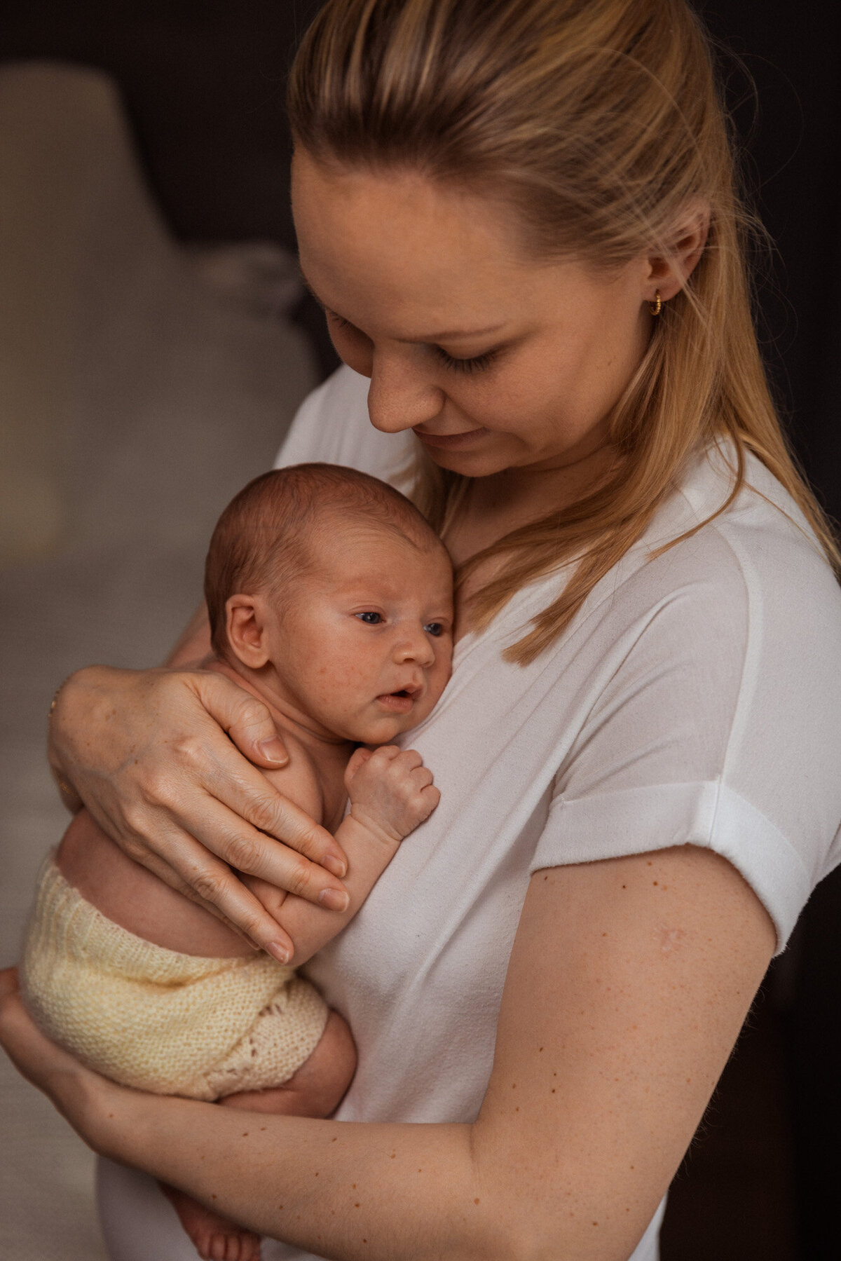 Livsstilsfoto av mor som holder babyen sin mot brystet sitt, tatt på skrå ovenfra og ned.