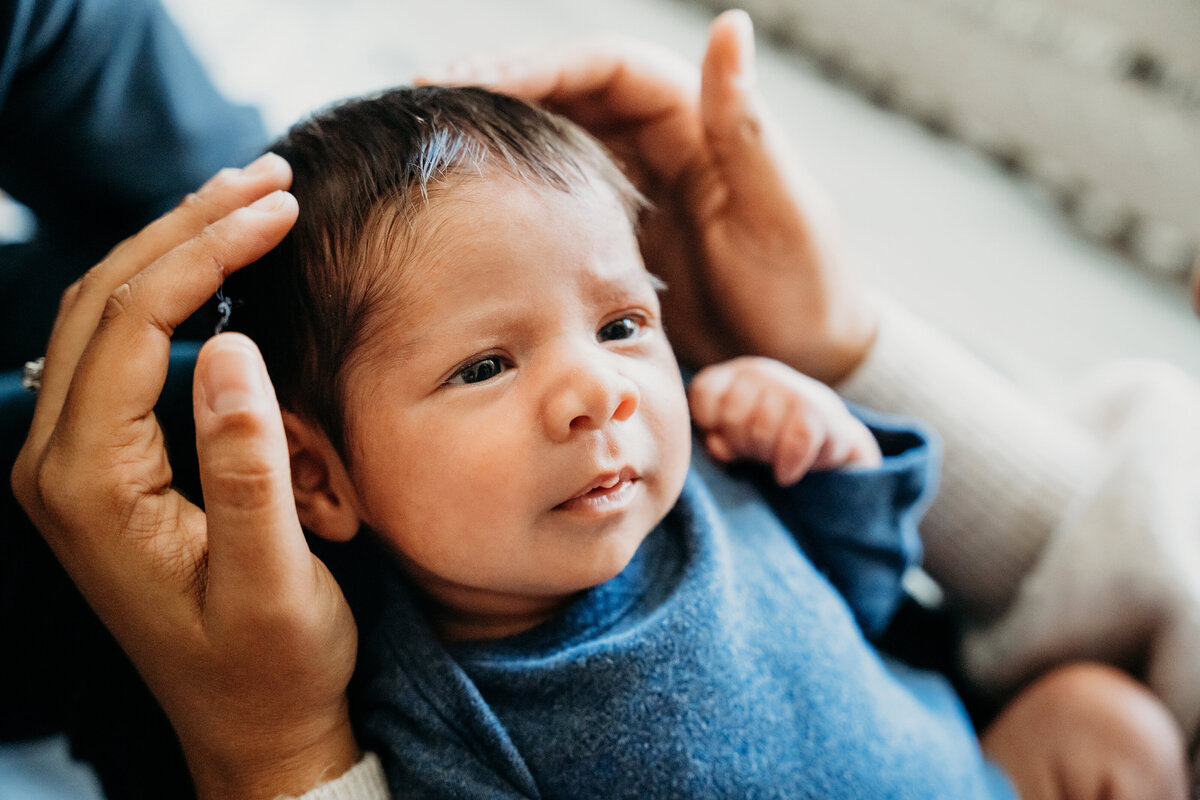 Newborn Photographer, a parent's hands hold baby