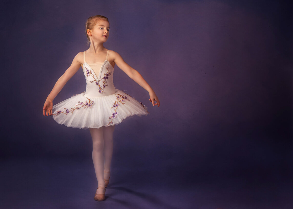 Elegant studio portrait of a young ballerina in a tutu, striking a graceful pose against a dark backdrop. Captured in Overland Park, Kansas, this artistic setup is perfect for families seeking creative and refined child photography.
