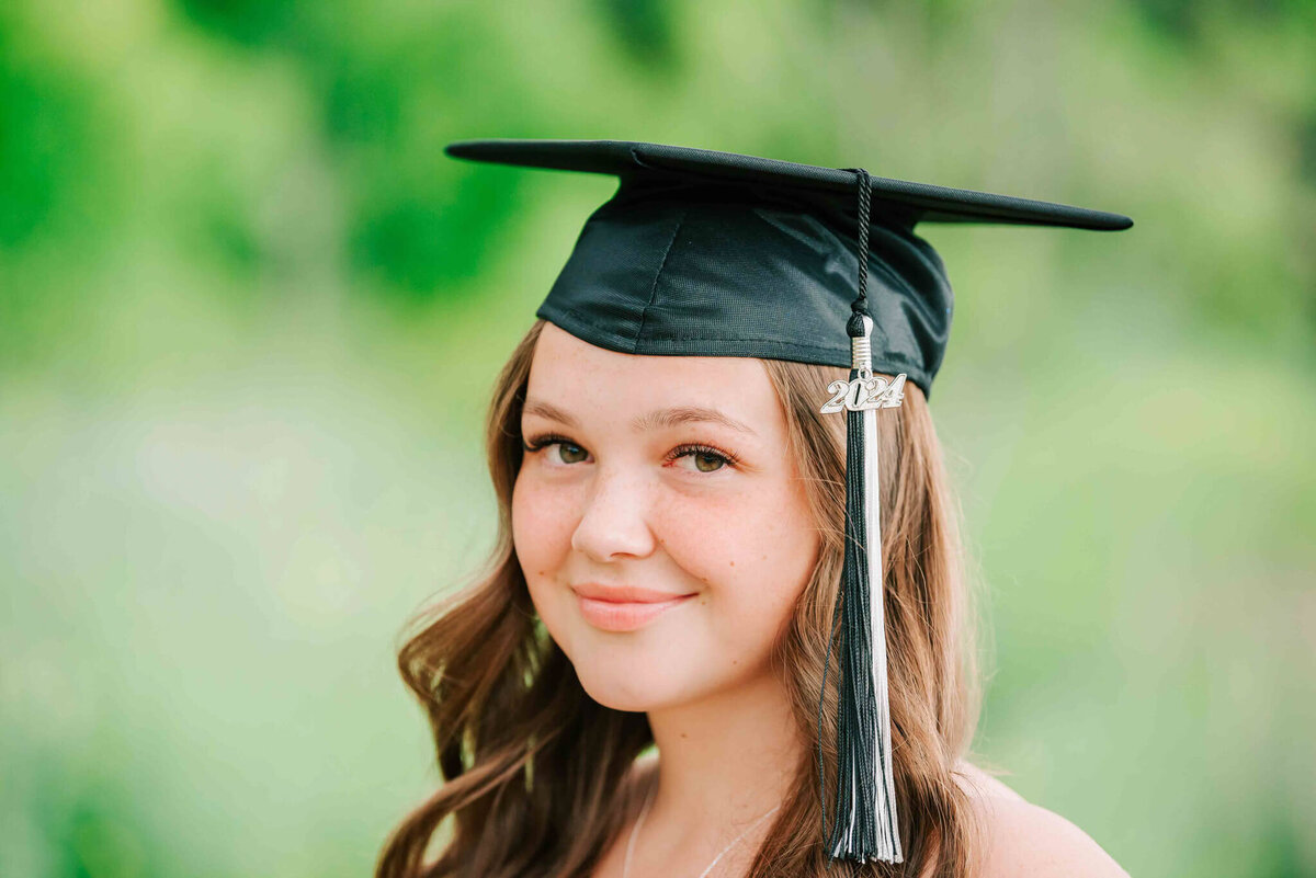 A close up portrait of her face wearing her grad cap. 