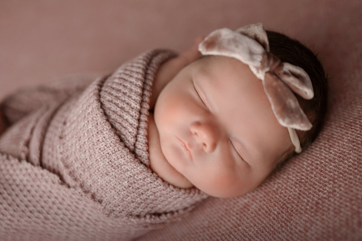 Closeup image of a newborn sleeping in knit swaddle