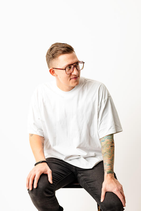 Man in glasses and white shirt looks off to side.