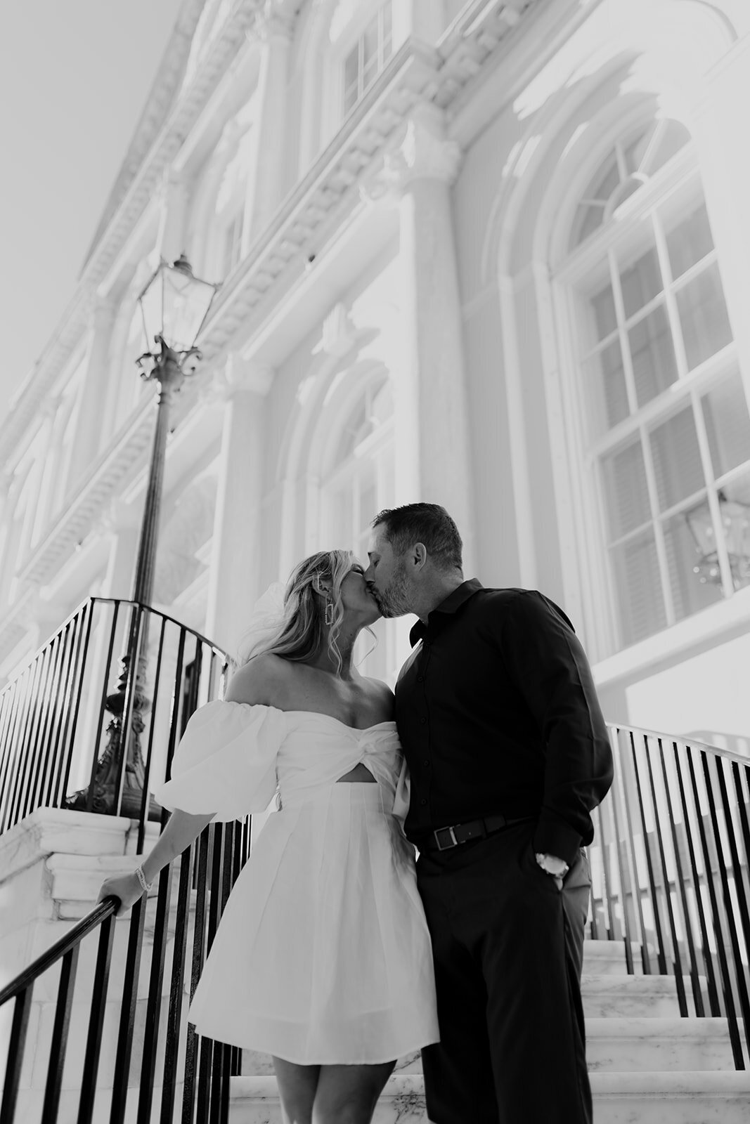 Couple sharing a kiss on stairs of Charleston City Hall during engagement photo session