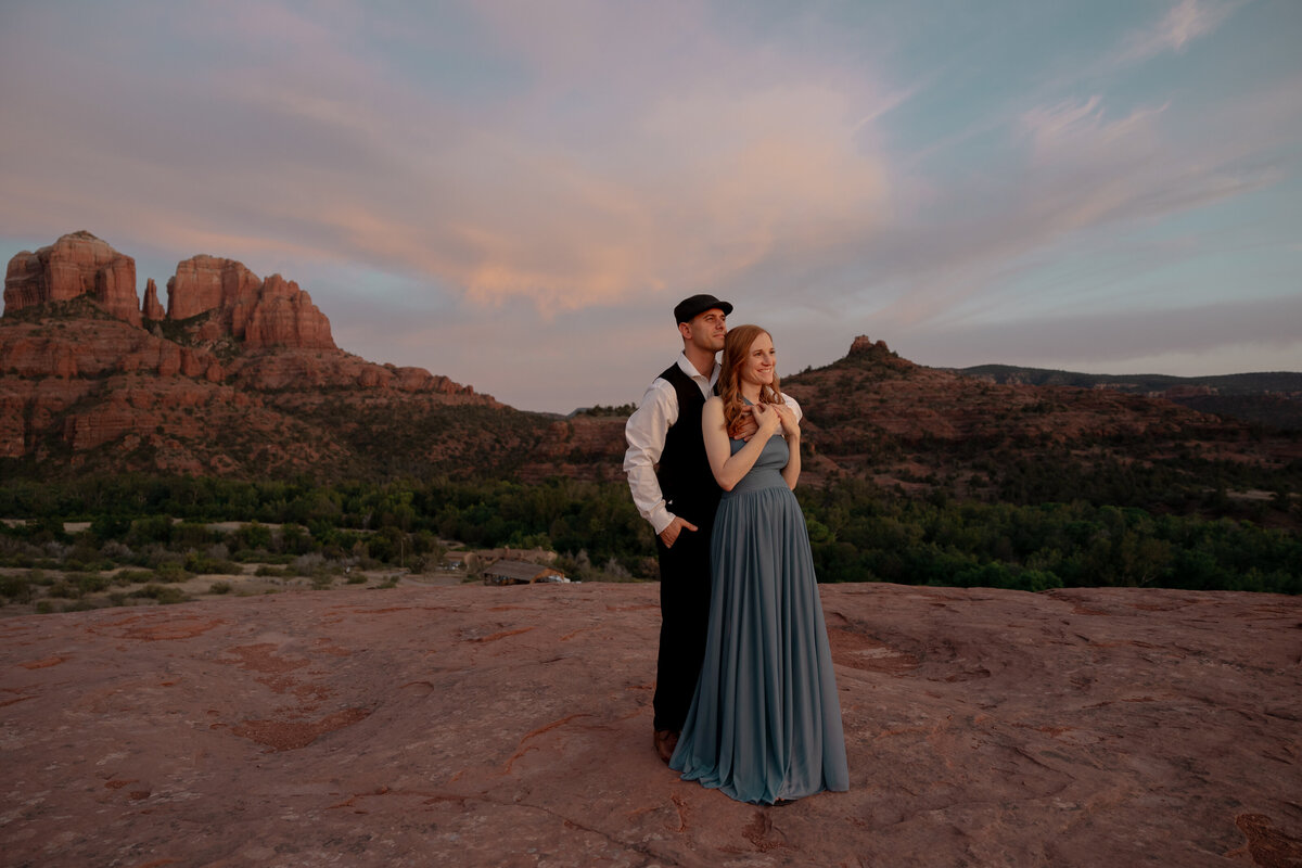 Couple standing against red rock backdrop during Sedona engagement session